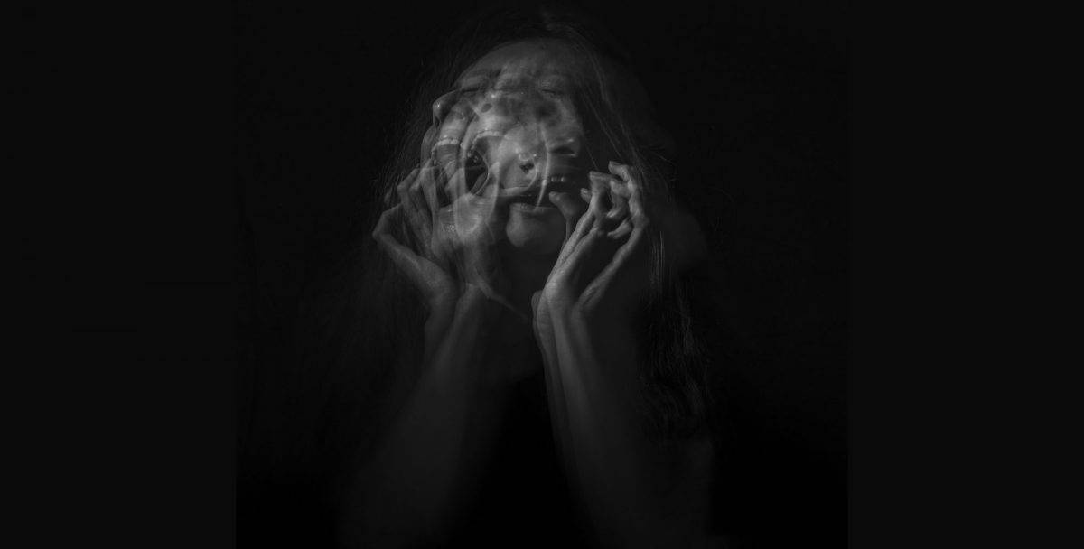 woman holding her face on black background