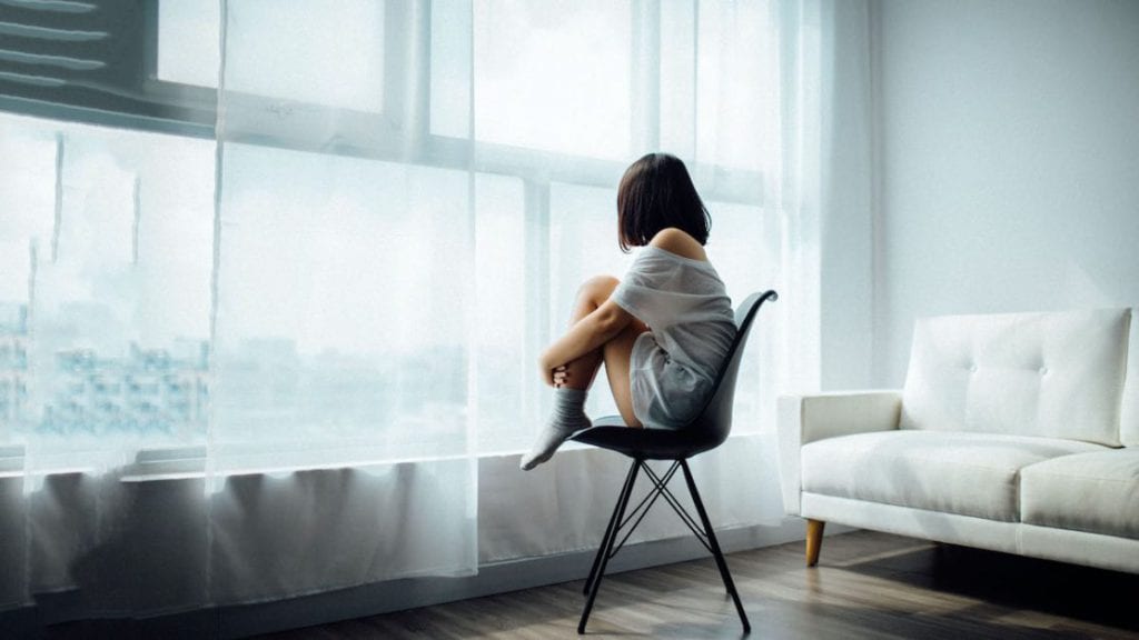 woman sitting on chair looking outside window