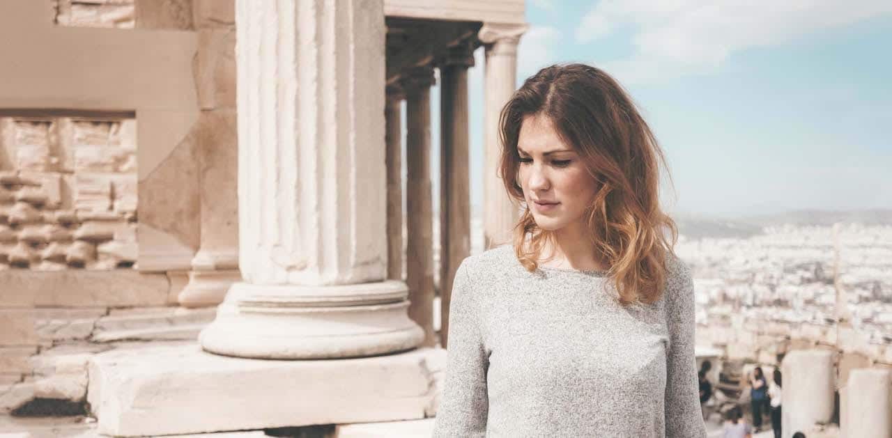 woman stood in front of ancient Greek building