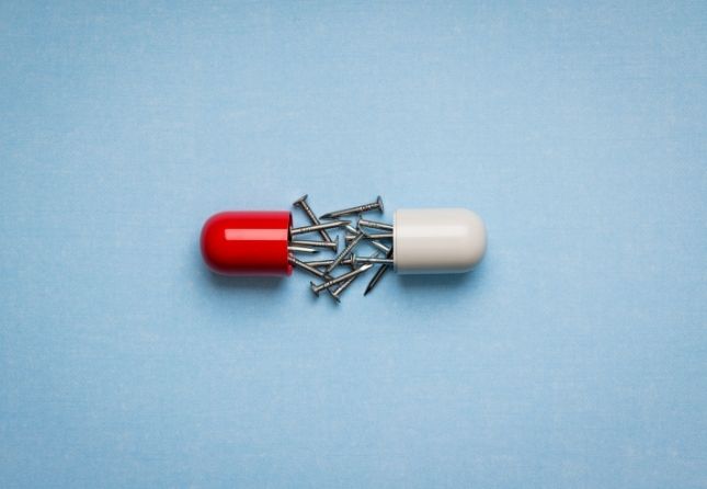 pill and nails on blue background