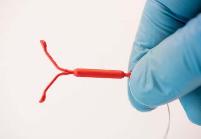 plastic gloved hand holding an IUD